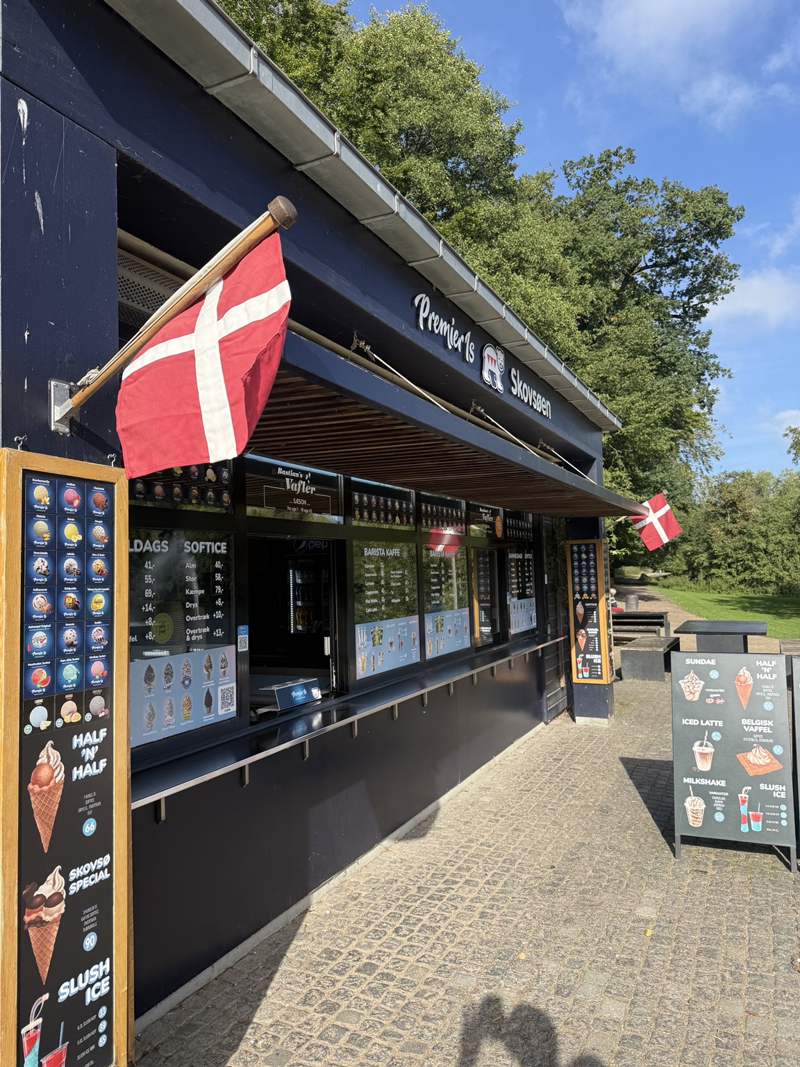 Butikken og siddepladserne ved skoven på en solrig dag
